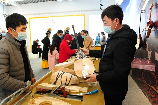 □在托里县展厅，冬不拉手工制作人（右）向市民介绍冬不拉制作工艺。