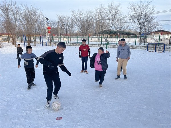 □加尔布拉克农场团结社区的孩子们在雪地踢足球。