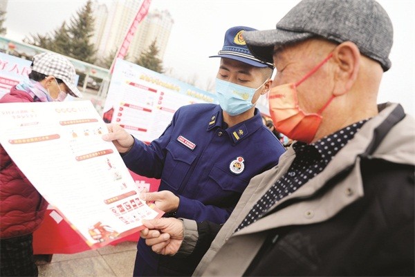 □地区消防救援支队指战员为市民讲解宣传手册。